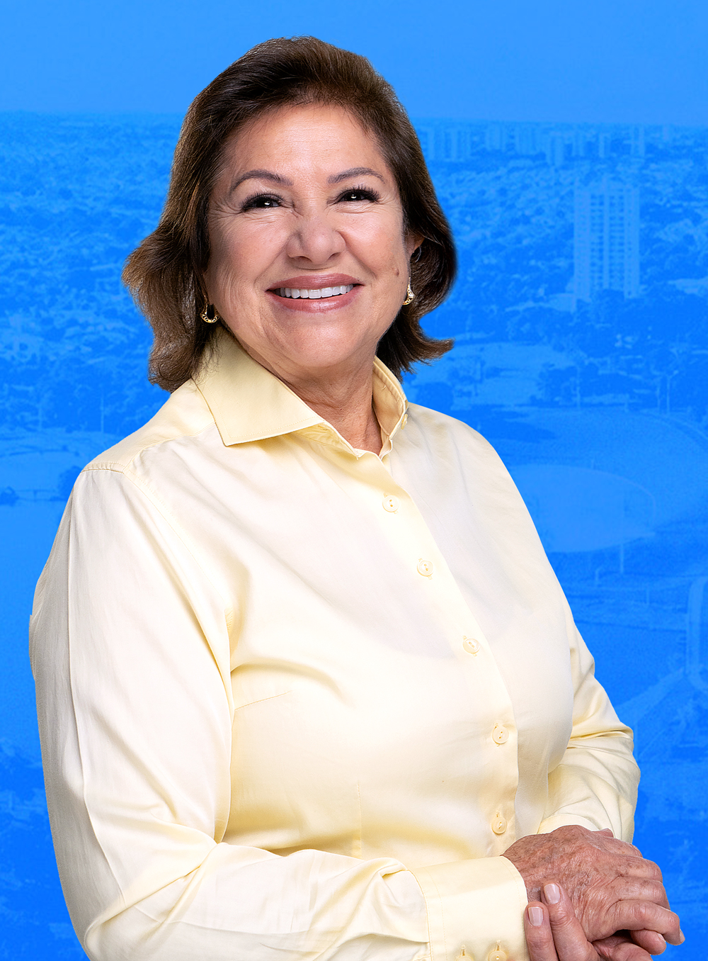 Dione Hashioka sorrindo, com vista aérea da cidade ao fundo